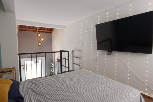 1 dormitorio con TV de pantalla plana en una pared con luces en Departamento Loft B en Orizaba