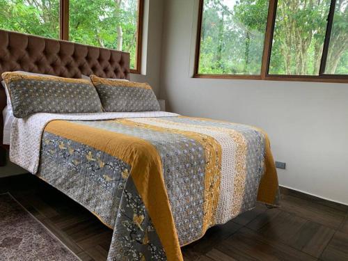 uma cama com uma colcha e almofadas num quarto em Potrerillos Ranch close to Boquete em Boquete