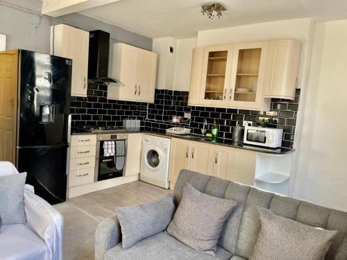 Comfortable flat in Stokes Croft في بريستول: غرفة معيشة مع أريكة ومطبخ