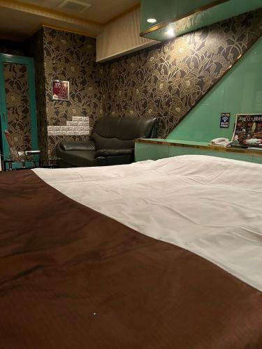 1 cama en una sala de espera con silla en おとぼけビーバーケセラセラ寝屋川, en Neyagawa