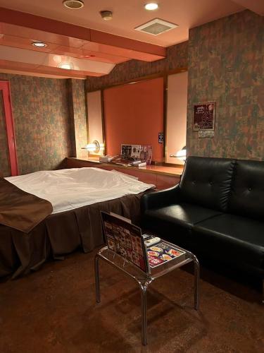 a room with a bed and a couch and a table at おとぼけビーバーケセラセラ寝屋川 in Neyagawa