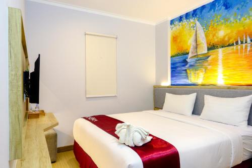 a bedroom with a bed with a painting on the wall at Kaloka Airport Hotel in Labu Sumbawa