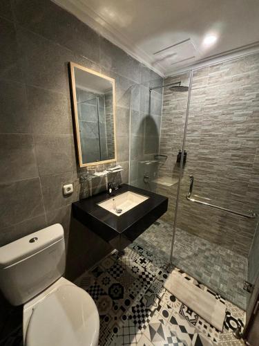 a bathroom with a toilet and a sink and a shower at Kaloka Airport Hotel in Labu Sumbawa