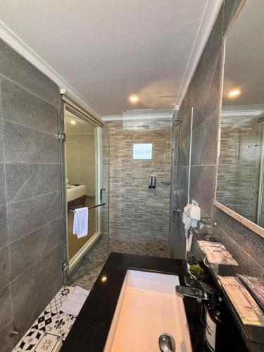 a bathroom with a shower and a sink and a tub at Kaloka Airport Hotel in Labu Sumbawa