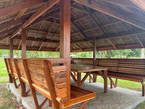 - une table de pique-nique en bois et des bancs sous un pavillon dans l'établissement The Beach House Long Beach, à New Agutaya