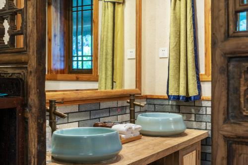 Yangshuo Ancient Garden Boutique Hotel في يانغتشو: حمام به مغسلتين زرقاء على منضدة
