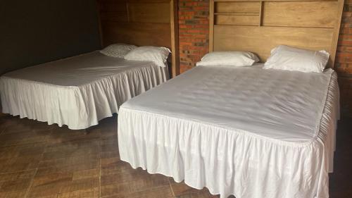 two beds with white sheets in a room at CHcasaquinta in Paraguarí