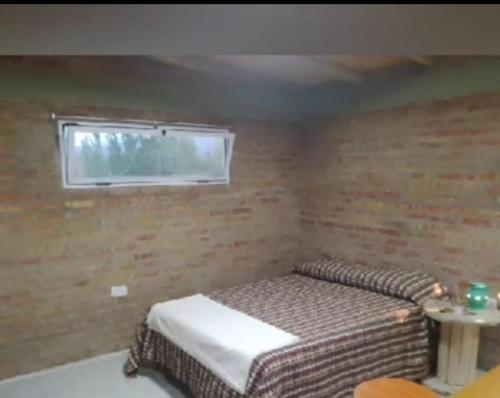 a small room with a bed and a window at Ushua Aike (Nuestro Lugar) in Los Antiguos
