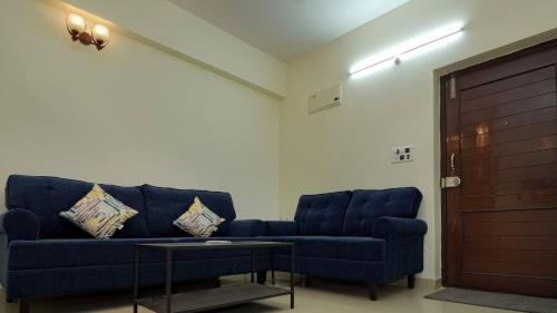 sala de estar con sofá azul y mesa en Deltin Royal Stays 3 Bedroom Apartment, en Hyderabad