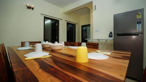 una mesa de madera con placas blancas y un objeto amarillo. en Deltin Royal Stays 3 Bedroom Apartment, en Hyderabad