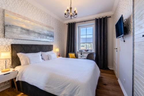 Un dormitorio con una gran cama blanca y una ventana en Hotel Villa Wahnfried Thiessow en Thiessow