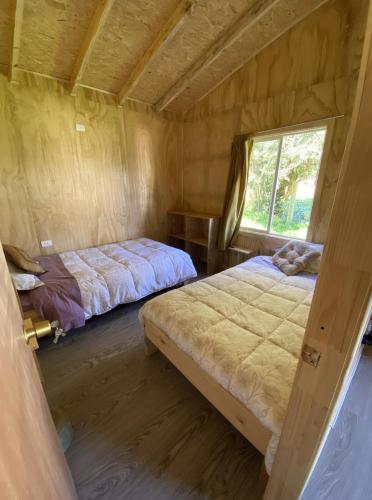 a bedroom with two beds and a window at Agradable cabaña para 4 personas en Hornopiren in Hornopiren