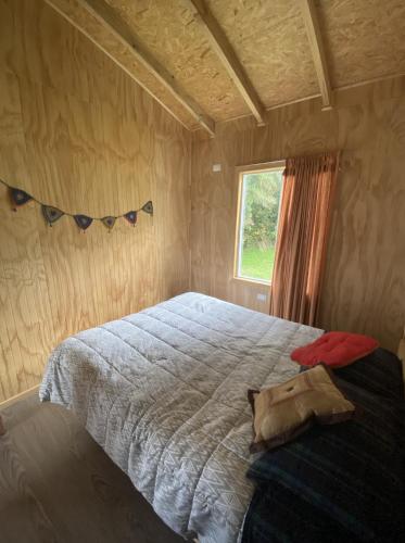 a bedroom with a large bed with a window at Agradable cabaña para 4 personas en Hornopiren in Hornopiren