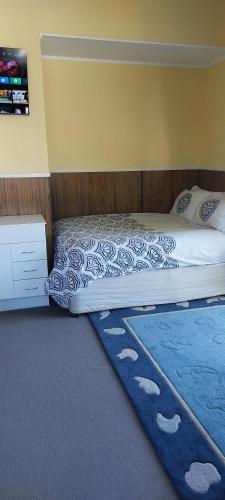 a bed with a blue rug in a bedroom at Bed and Breakfast Happy Home Taupo Accommodation in Taupo