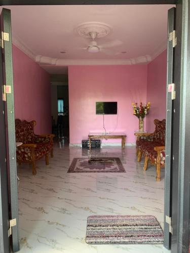 Kampong Sungai LayarにあるTeratak Kasih Homestayのピンクの壁の客室で、テーブルと椅子が備わります。