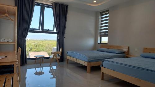 a bedroom with two beds and a large window at Windy Homestay Phan Thiết in Phan Thiet