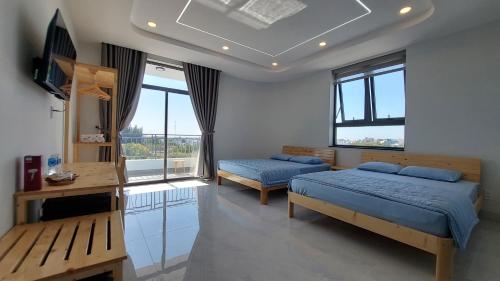 um quarto com 2 camas, uma televisão e janelas em Windy Homestay Phan Thiết em Phan Thiet