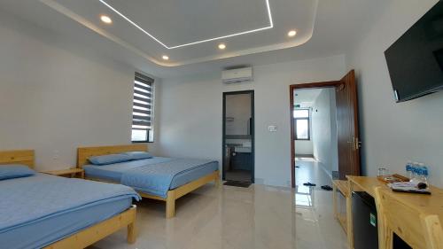 a bedroom with two beds and a flat screen tv at Windy Homestay Phan Thiết in Phan Thiet