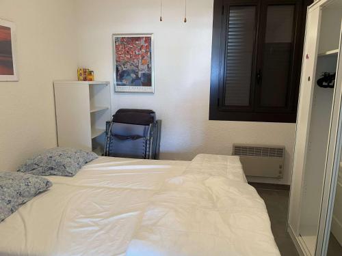 une chambre avec un grand lit blanc et une chaise dans l'établissement T2 Le Barcarès - Terrasse, Piscine, Parking - FR-1-195-106, au Barcarès
