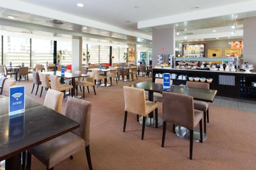 a restaurant with tables and chairs and a bar at Holiday Inn Express Lisbon-Oeiras by IHG in Oeiras