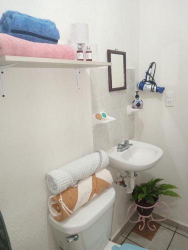 a bathroom with a toilet and a sink with towels at Breezy & Cancunian Villa in Cancún