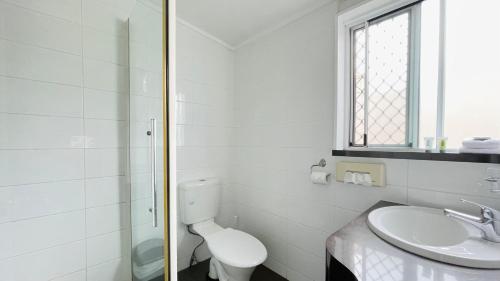 a white bathroom with a toilet and a sink at Motel Myall in Dalby