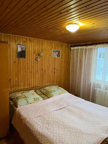 1 dormitorio con 1 cama en una pared de madera en Cottage u Romana, en Yaremche