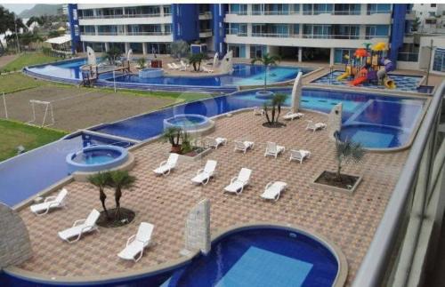 a swimming pool with white lounge chairs and a resort at Tonsupa Diamond Beach in Tonsupa