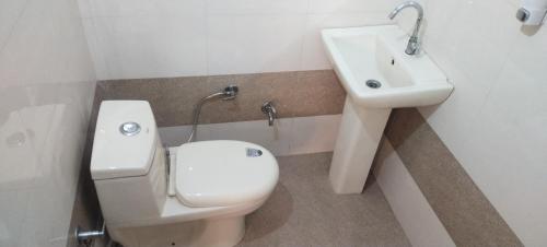 a bathroom with a white toilet and a sink at RANGBAARI STAYS & CAFE in Jodhpur