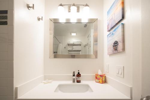 a white bathroom with a sink and a mirror at Bright Pacifica Townhouse in Pacifica