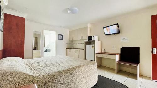 a bedroom with a bed and a desk and a refrigerator at Motel Myall in Dalby