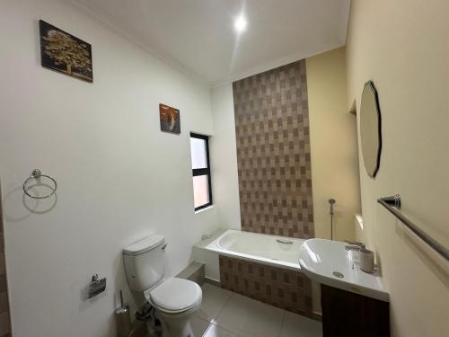 a bathroom with a tub and a toilet and a sink at Six64 on KINGSWAY B5 in Amanzimtoti