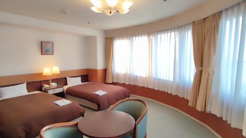 a hotel room with two beds and a table and chairs at Utazu Grand Hotel in Utazu