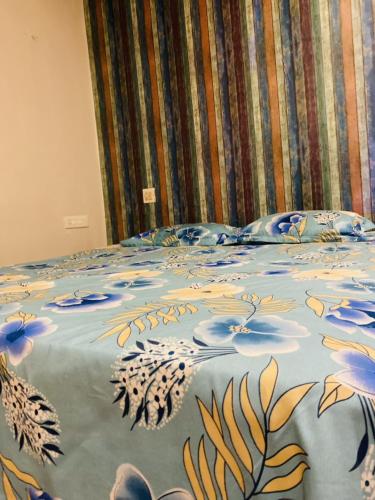 a bed with a blue blanket with flowers on it at Alnour hometstay in Cochin