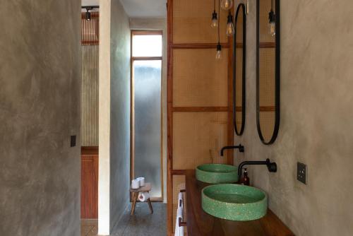 a bathroom with two green sinks and a mirror at Be Zanzibar Boutique Hotel in Mfumbwi