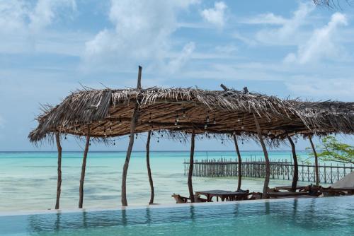 a straw hut on a beach with the ocean at Be Zanzibar Boutique Hotel in Mfumbwi