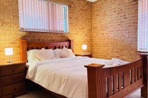 1 dormitorio con 1 cama de madera y 2 ventanas en Dhanda Farm Bathurst, en Raglan