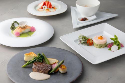 a table with white plates of food on them at Lake Biwa Marriott Hotel in Moriyama