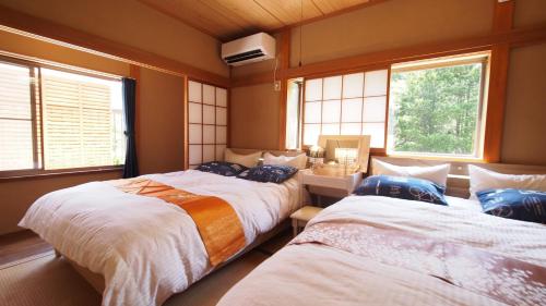 two beds in a room with two windows at BBQ施設徒歩圏内&露天風呂付き&箱根を大勢で遊びたい &癒されたい in Gora