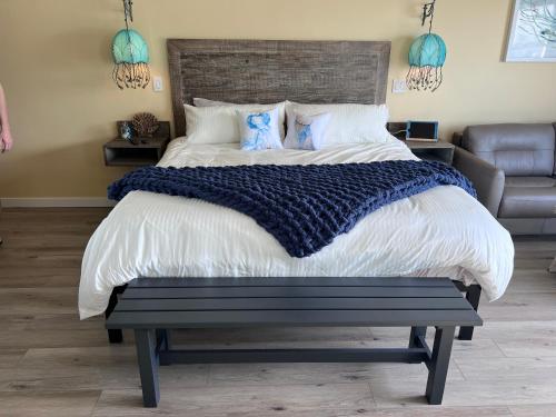 a bedroom with a large bed with a bench in it at HarborWalk Inn in Morro Bay