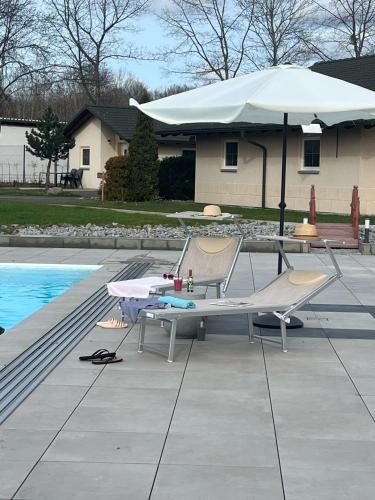 a table and two chairs and an umbrella next to a pool at Natur- und Aktivresort Senftenberg in Schipkau