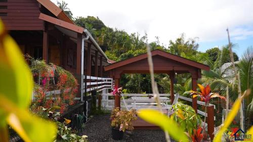 een houten pergola met een tafel en een aantal planten bij Chalet des laves in Sainte-Rose