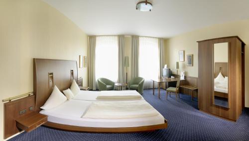 a hotel room with a large bed and a desk at Victoria Hotel in Minden