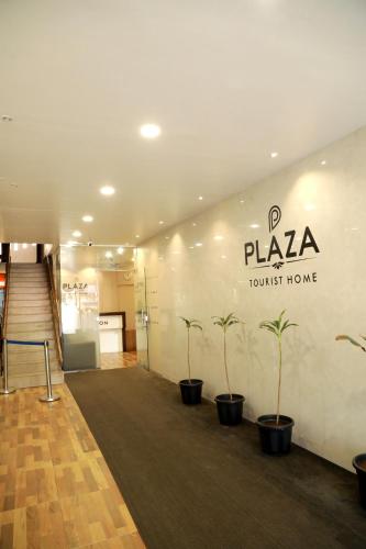 a lobby with potted plants and a sign on a wall at Plaza Tourist Home in Kannur