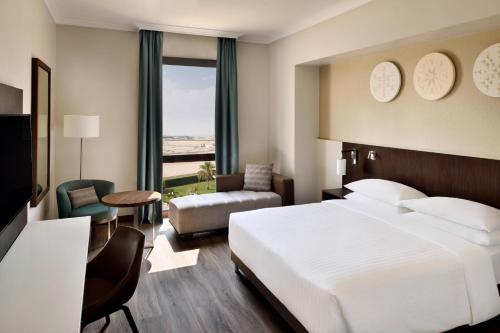 Riyadh Airport Marriott Hotel في الرياض: غرفة نوم بسرير ابيض كبير وغرفة معيشة