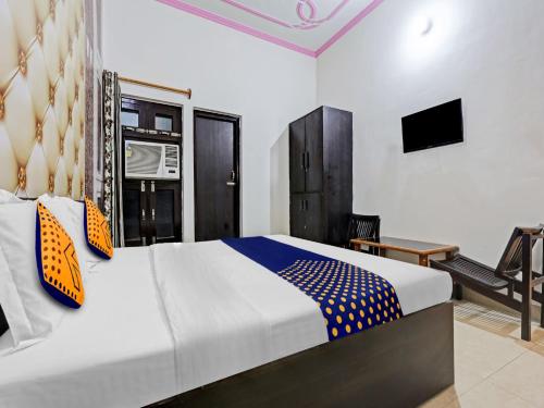 ein Schlafzimmer mit einem Bett, einem Stuhl und einem TV in der Unterkunft SPOT ON 81167 Hotel ASDR in Rudrapur