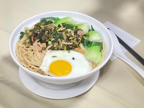 a bowl of food with an egg on top of noodles at Magnificent International Hotel in Shanghai