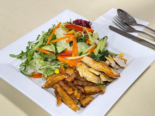 a white plate of food with a salad and fries at Magnificent International Hotel in Shanghai
