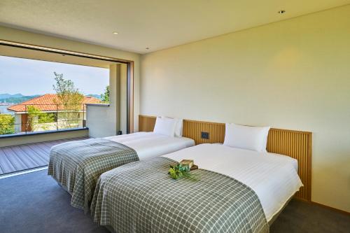 2 bedden in een hotelkamer met een groot raam bij 瀬戸内ゴルフリゾートヴィラ 