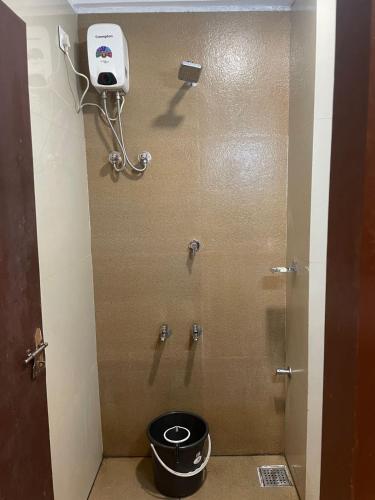 a bathroom stall with a shower with a bucket at Plaza Tourist Home in Kannur